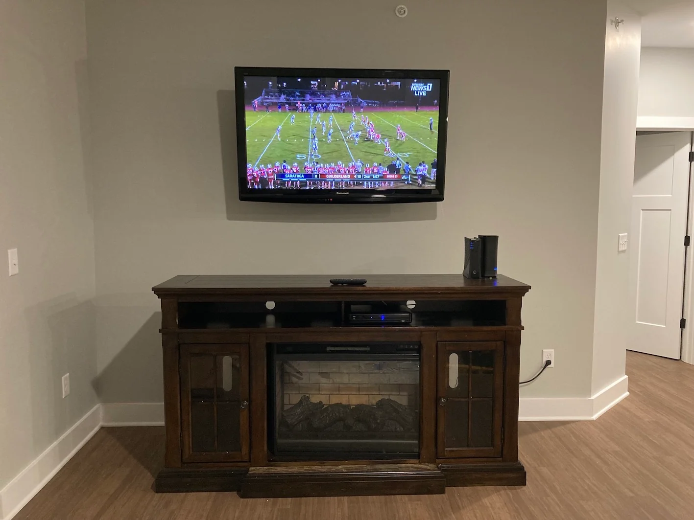 Wall-mounted television above a dark wood media cabinet with glass doors.