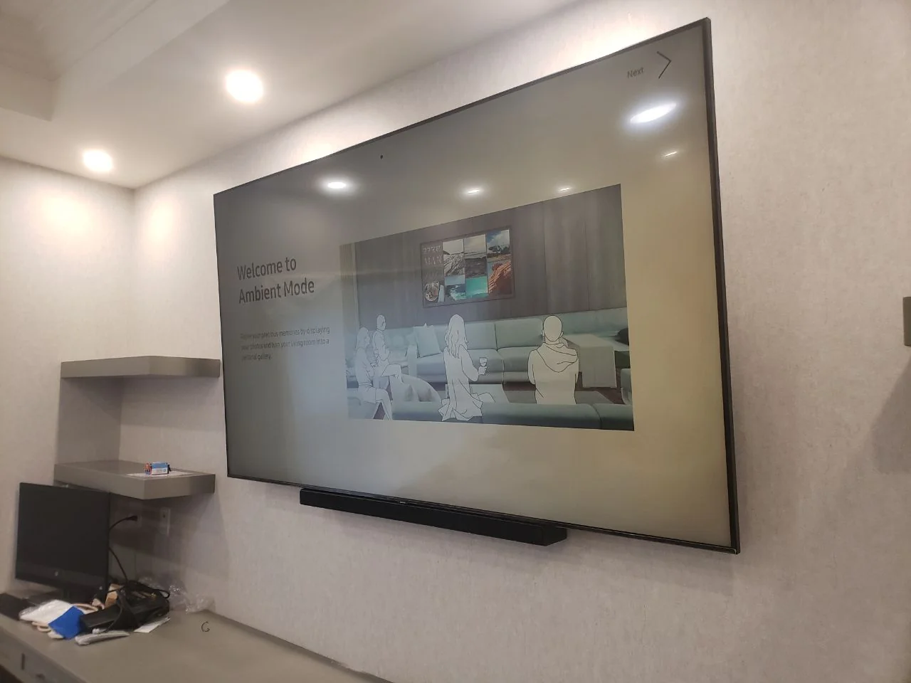 Television above gray built-in cabinets and floating shelves, viewed from the side.