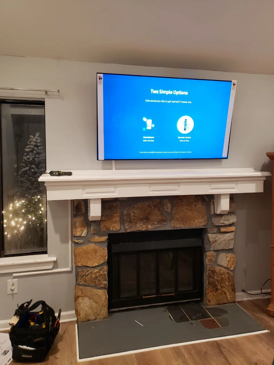 Television displaying a setup screen above a stone fireplace with a white mantel.