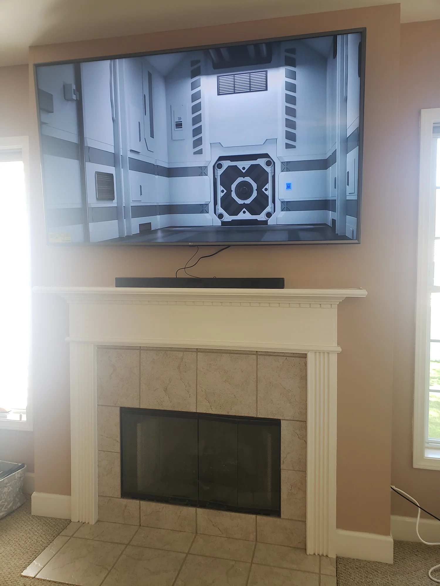 Wall-mounted television centered above a tiled fireplace and white mantel.