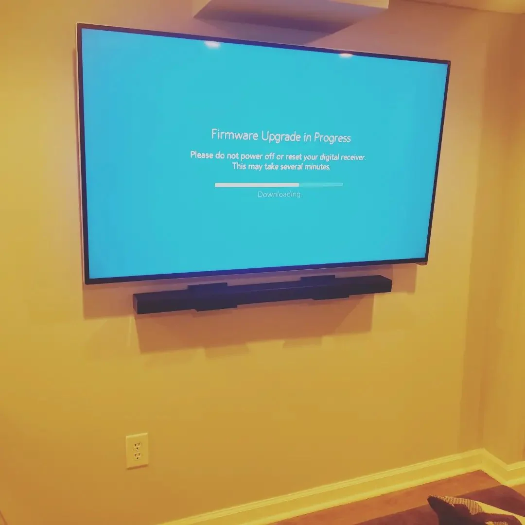 Wall-mounted television with a soundbar beneath it, displaying a setup screen.