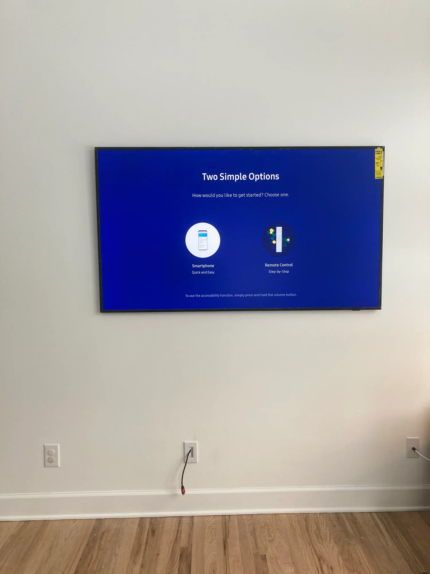 Television mounted on a white wall above a recessed cable box and wall outlets.